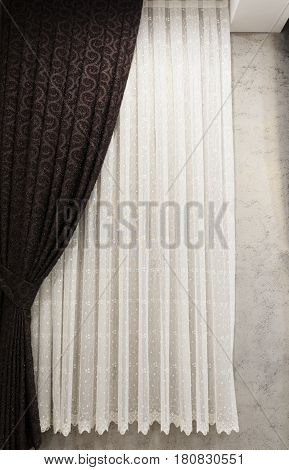 Beautifully draped long curtain on the window in the room. Close up of piled curtain. Luxury curtain home decor. Brown panels. White lace drapery