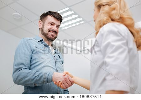 Was nice working with you. Delighted doctor and her happy patient shaking hands with a doctor and expressing his gratitude after undergoing some dental procedures