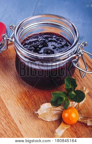 Berry jam. Glass jar of berry jam on blue background. Preserved fruits. Homemade berry jam in jar covered.