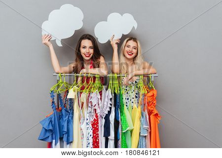 Cheerful young women with blank copy spaces near hager while shopping isolated over grey background