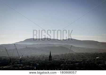 Edinburgh in the distance with hills in the background on a foggy / misty morning