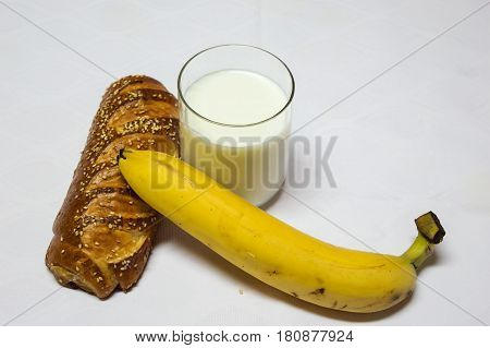 Healty breakfast roll with sesamo banana and glass of fresh milk. Backery bread breakfast. Roll Pastry banana and Glass of Milk Isolated on White Background