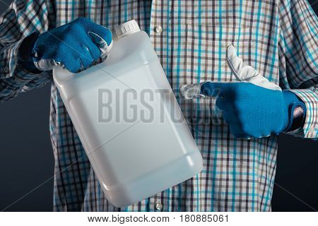Unrecognizable male farmer with unlabeled plastic tank canister containing pesticides for plant processing in agriculture