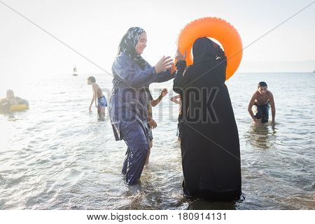 Muslim Arabic women at sea beach in burkini