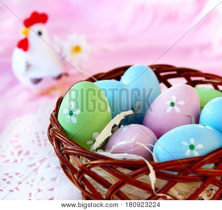 Easter eggs in a wicker basket on a pink background.
