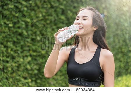 Asian woman in sportswear drinking water on natural background. freshness happiness relaxing.
