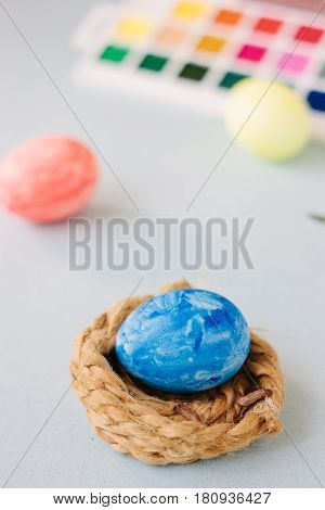 Deep Blue Easter Egg On Nest Over Bright Background.