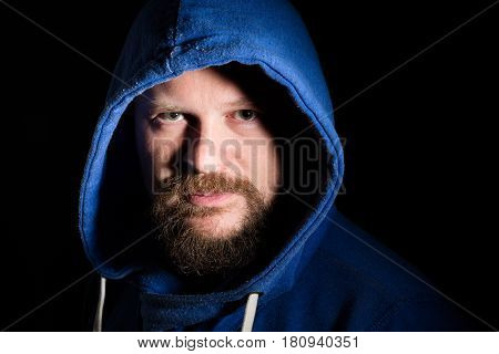 Solid bearded middle-aged man in a hood  portrait on black background
