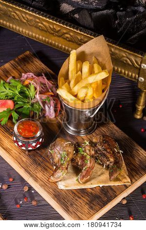 The uvulas of a ram fried on coals are served with onions salad, French fries and spices