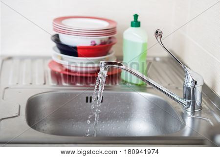 Cleaning dishware kitchen sink sponge washing dish. Close up of female hands in yellow protective rubber gloves washing