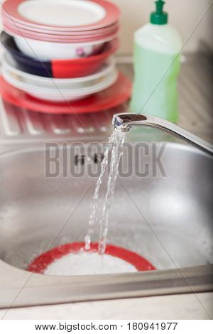 Cleaning dishware kitchen sink sponge washing dish. Close up of female hands in yellow protective rubber gloves washing