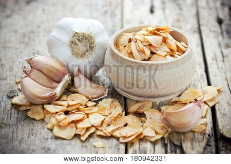Dried garlic flakes or garlic chips and raw garlic bulb on old wooden background
