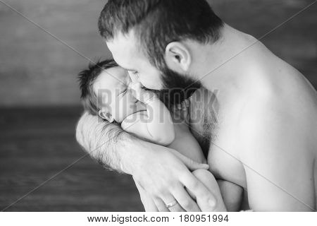 Newborn baby and dad. Happy father holding and plays with his baby boy indoors. black and white photo