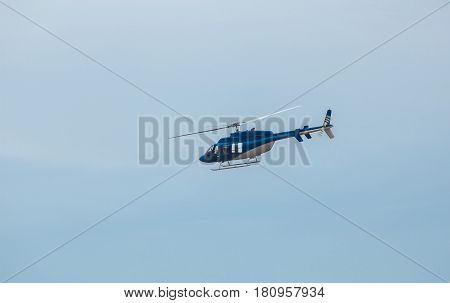 A large blue helicopter is flying against the blue sky.