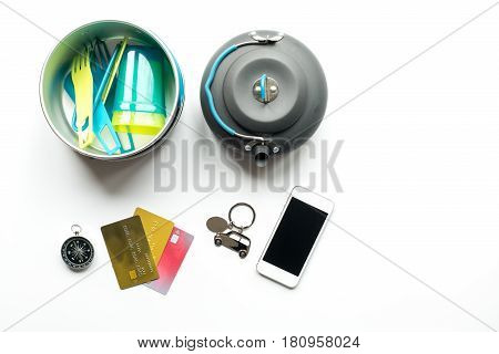 traveller lifestyle items with compass and plactic dishes on white table background top view