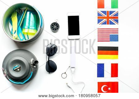 traveller lifestyle items with flags and plactic dishes on white table background top view