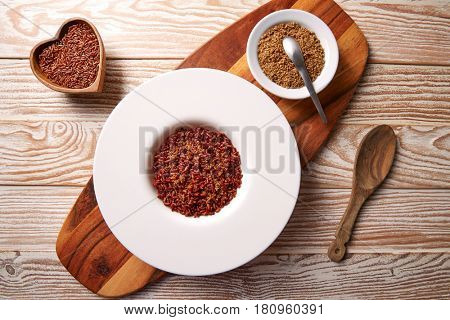 Red wild rice with sesame gomasio seasoning in a white plate over wooden board