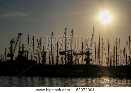 Shape of boat masts and cranes at sunset in Toulon port France