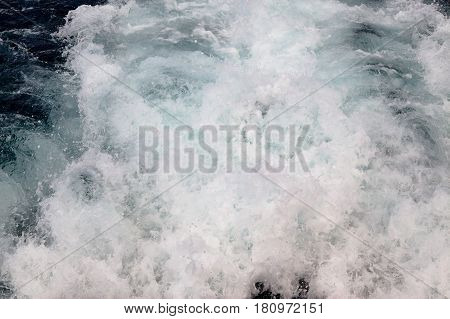 Trail on water surface behind of cruise ship.