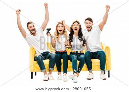 Excited Young Friends Sitting On Couch And Playing With Joysticks Isolated On White