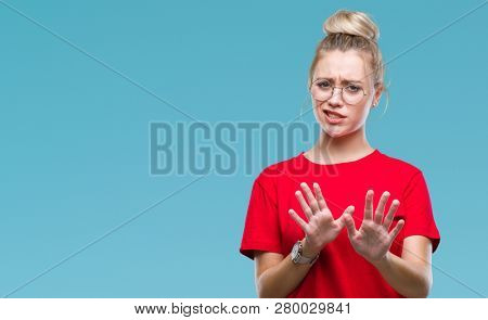 Young blonde woman wearing glasses over isolated background disgusted expression, displeased and fearful doing disgust face because aversion reaction. With hands raised. Annoying concept.