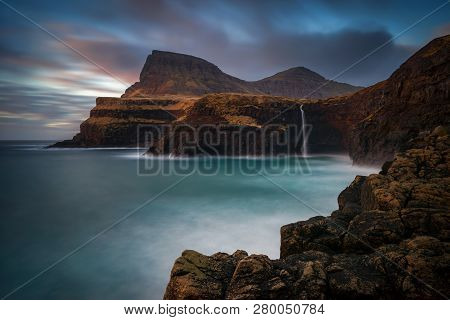 Mulafossur Waterfall On Vagar Island In Colorful Sunset, Faroe Islands