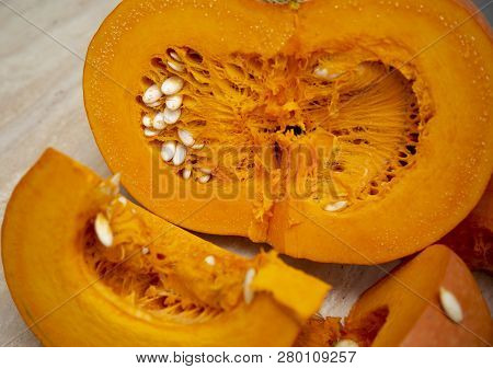 Juicy Bright And Ripe Pumpkin Is Cut, Located Next To A Slice With Seeds. Pumpkin Oval-shaped Hard C