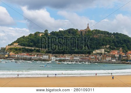 Top View Of A Wide Sandy Beach And Bay With Boats On The Background Of A Mountain With A Large Statu