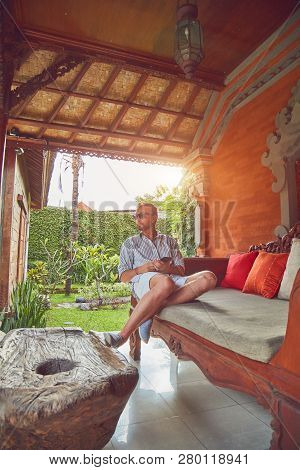 Man Using Smart Phone On A Terrace Sofa In Summertime.