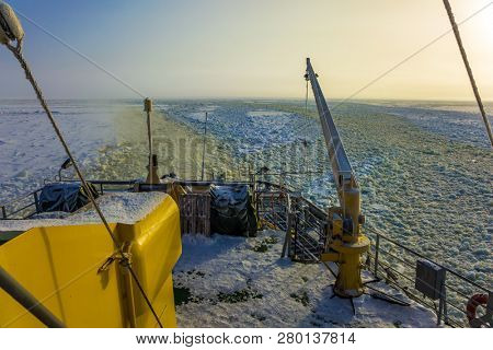  The concept of active and extreme tourism. Dim polar sun in Lapland. The strip of ice crumb spreads behind the icebreaker. The excursion to the arctic tourist cruise on the sea icebound