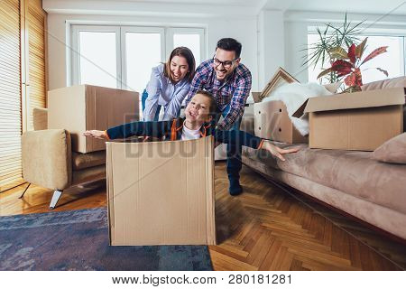 Happy Family Moving Home With Boxes Around, And Having Fun.