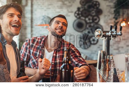 Men Watching Football Match And Drinking Beer, In Sport Bar