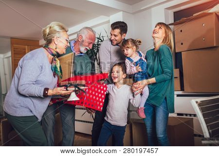 Grandmother And Grandfather Bring A Gift For Moving Into A New Apartment To Their Children
