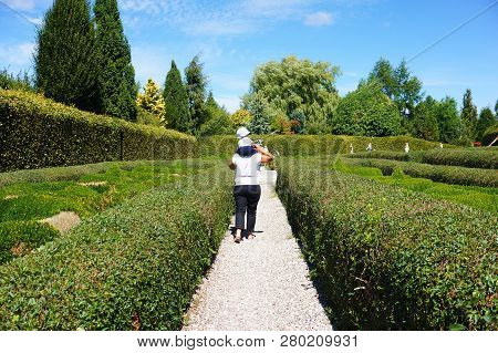 Dobrzyca, Poland - August 6, 2018: Woman Walking With Toddler On Her Shoulders In A Labyrinth At The