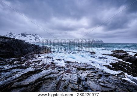 Waves of Norwegian sea crushing at rocky coast in fjord. Vikten, Lofoten islands, Norway