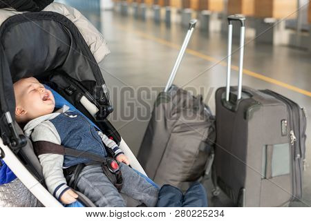 Screaming Baby Boy Sitting In Stroller Near Luggage At Airport Terminal. Child In Carriage Near Chec