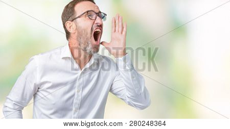 Handsome middle age elegant senior business man wearing glasses over isolated background shouting and screaming loud to side with hand on mouth. Communication concept.