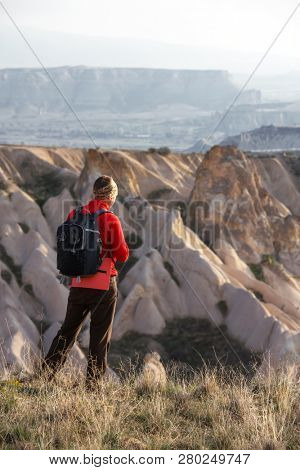 Amazing day in Cappadocia mountains, Turkey. Photographer in red jacket taking photo of amazing hills. Landscape photography