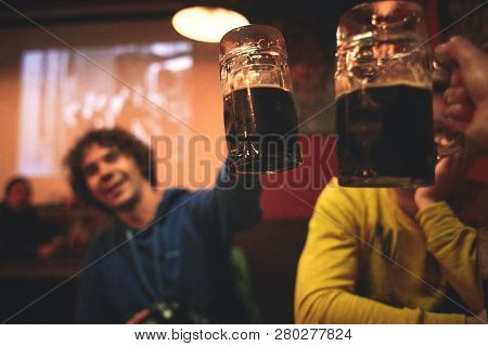 Friends Sitting In The Pub With Glasses Of Beer