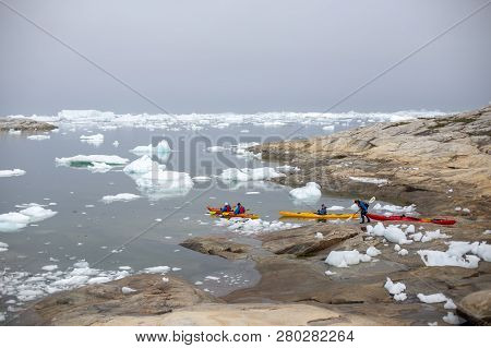 Ilulissat, Greenland - July 1, 2018: Group Of People Kayaking In Between Icebergs At Ilulissat Icefj