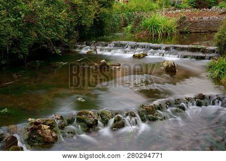 Long Exposure Of The River Flowing Through Cheddar Village In Somerset