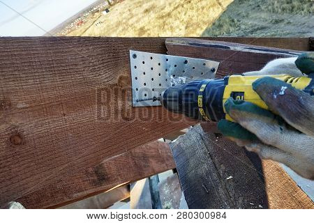 The Worker Screw The Screw Into A Screw Plate, A Roof Rack Of The Building Can Be Seen
