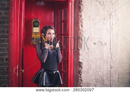 Old Style Red Telephone Booth With Picture Of Group Of Girls In Bikinis On Glass To Make It Look Lik