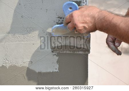 Hands Of An Old Manual Worker With Wall Plastering Tools Renovating House. Plasterer Renovating Outd