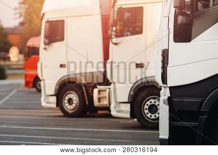 Trucking On Trucks, White Cars Are Parked In Parking Lot, Ready To Start Logistics Route.