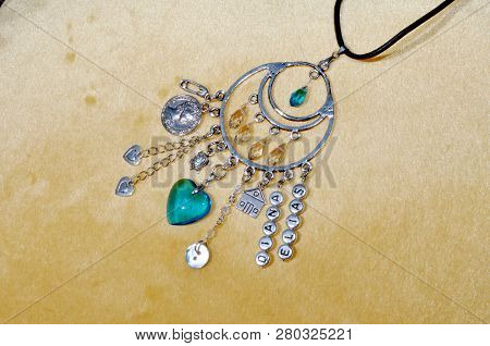 Protective Power. Jewelry Charm Or Talisman. Luck Amulet On Textile Background. Name Amulet For Good