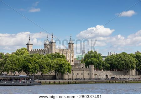 The famous White Tower and the Tower of London from South Bank across the River Thames.  Popular historical tourist attraction on a summer day. Logos removed and people not recognisable at 100 percent