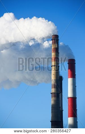 White Smoke Comes From Pipes Against Blue Sky. Problem Harmful Emissions And Air Pollution Of Centra
