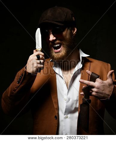 Mafia Bearded Man In White Shirt, Jacket, Cap Hat And Sunglesses Holds Big Knife And Scabbard And Sh