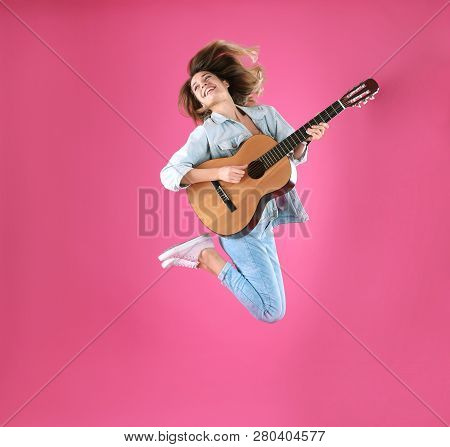 Young Woman Playing Acoustic Guitar On Color Background